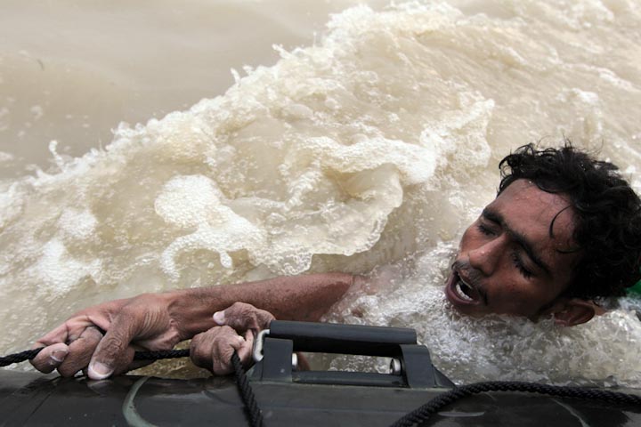 Жертва наводнения Мухаммед Наваз держится за плот ВМС Пакистана во время спасательной операции в Суккуре, Пакистан, 10 августа 2010 года. Пакистан пострадал от сильнейшего за последние 80 лет наводнения, в результате которого миллионы людей остались без крыши над головой.